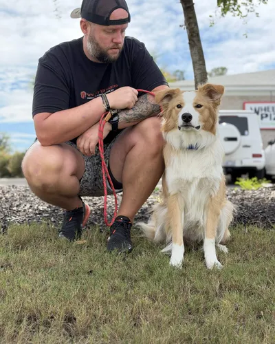 Zack Barkley kneeling with a sheltie mix