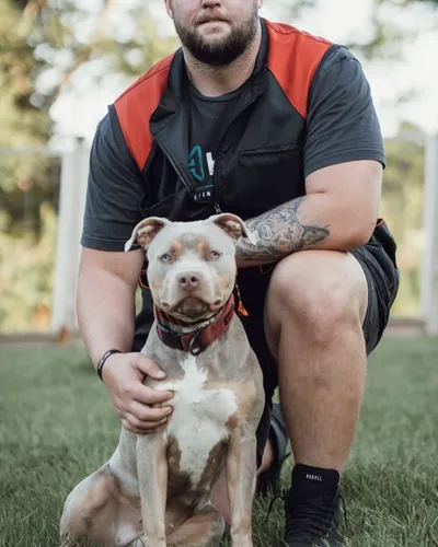 Zack Barkley kneeling with a pit bull